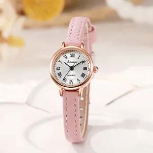 Reloj elegante de mujer en oro rosa con números romanos y correa de cuero rosa sobre cerámica