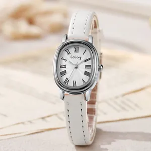 Détail d'une montre à quartz ovale argentée avec bracelet en cuir blanc sur journal