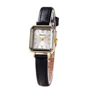 Montre vintage rectangulaire pour femme avec boîtier doré et bracelet en cuir noir sur blanc