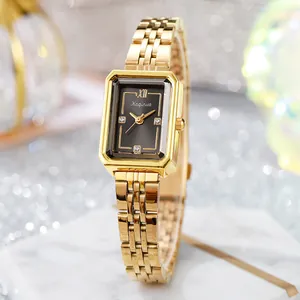 Close-up of square gold watch with black dial and diamond markers on marble surface