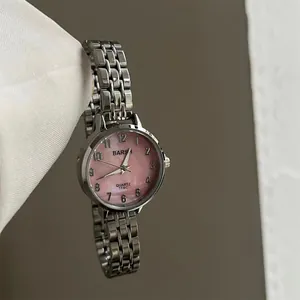 Détail d'une montre en acier argenté avec cadran en nacre rose et chiffres arabes noirs