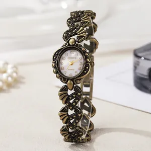 Detail of vintage gold bracelet watch showing white dial with Arabic numerals