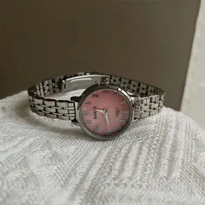 Détail de montre à bracelet en acier argenté avec cadran rose et chiffres arabes
