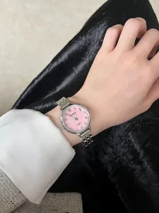 Détail d'une montre à quartz pour femme avec bracelet en acier argenté et cadran rose au poignet