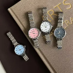 Montres quartz en acier inoxydable pour femmes avec cadrans colorés posées sur des livres anciens