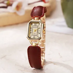 Detail der goldenen achteckigen Vintage-Uhr mit weinrotem Leder- und Kettenarmband