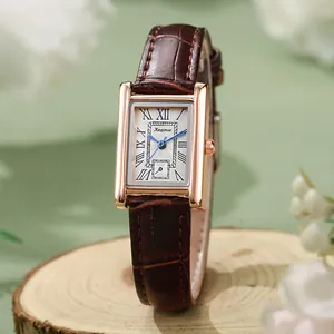 Detail van roségouden rechthoekig horloge met bruine leren band en Romeinse cijfers