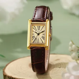 Vintage square women's watch with champagne dial and brown leather strap on wooden stand