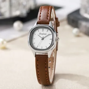 Detail of tonneau-shaped silver alloy watch case with white dial and brown leather strap