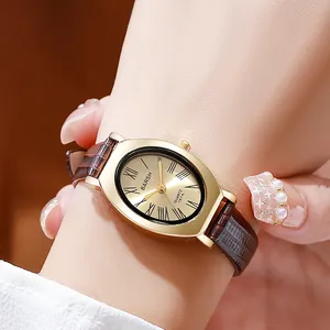 Vintage women's oval gold quartz watch with a brown leather strap shown on wrist