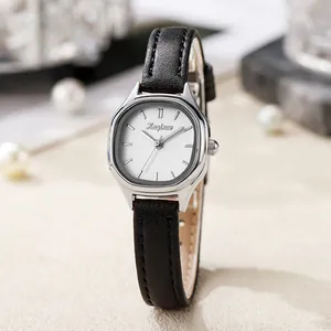 Detail of vintage silver tonneau-shaped watch with white dial and black leather strap