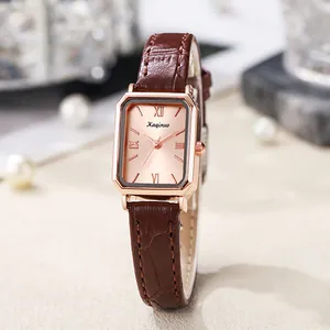 Detail van vierkant roségouden horloge met champagne wijzerplaat en bruine leren band