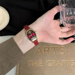 Montre quartz ovale élégante avec bracelet en cuir rouge au poignet d une femme avec accessoires