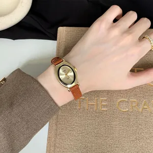 Montre à quartz vintage ovale dorée élégante avec bracelet en cuir marron au poignet