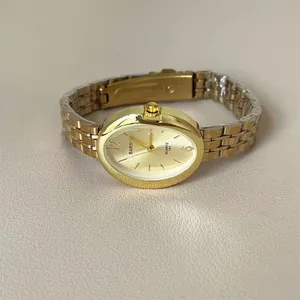 Dettaglio di un orologio dorato da donna ovale con cinturino a catena in metallo