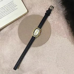 Detailweergave van het gouden dameshorloge met kristallen bezel en zwarte lederen band