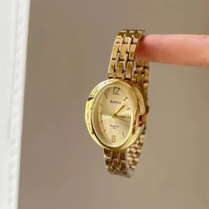 Dettaglio di orologio al quarzo ovale dorato con cinturino in metallo e quadrante