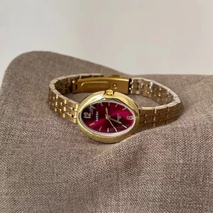 Dettaglio dell'orologio ovale di lusso in oro con quadrante rosso e cinturino in metallo