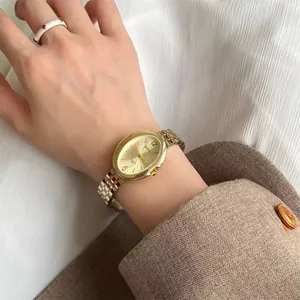 Dettaglio orologio al quarzo ovale dorato con anello in smalto bianco e gemma rossa