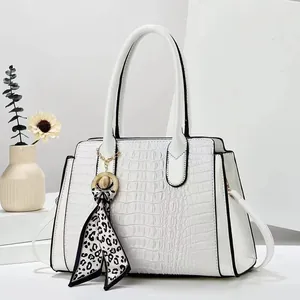 Detail of white crocodile-embossed handbag with leopard silk scarf and gold hardware accents