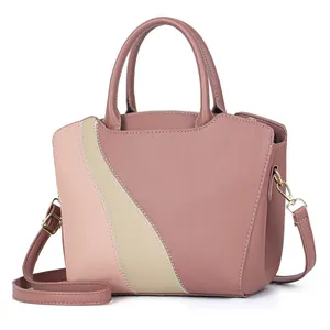 Detail van roze lederen handtas met beige contraststrepen en goudkleurige hardware