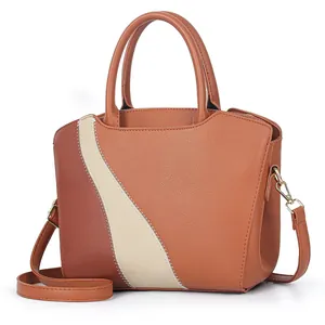 Detail van contraststiksels en ivoorkleurige patchwork op bruine leren handtas