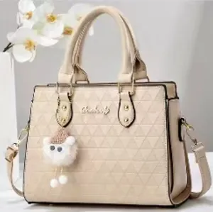 Détail du sac beige avec motif géométrique gaufré et petit pendentif mouton en peluche