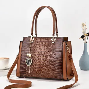 Détail macro du sac en cuir marron texture crocodile avec pendentif cœur élégant