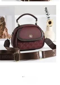 Close-up of wine red shell handbag showing lychee leather texture and golden metal logo