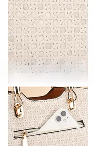 Detail of cream woven texture handbag showing golden metal rings and smartphone pocket