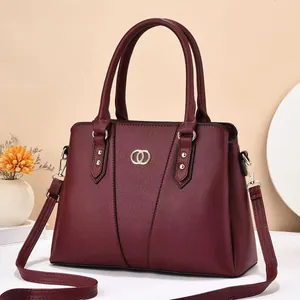 Detail of burgundy textured leather handbag with gold metal ring and detachable shoulder strap