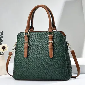 Dettaglio della borsa tote intrecciata verde scuro con manici in pelle marrone e fibbie oro