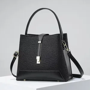 Detail of black lace and leather handbag with gold clasp on a minimalist stand