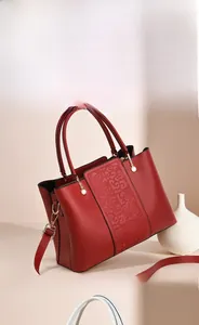 Detail of wine red leather tote with vintage embroidery and gold hardware accents