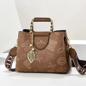Detailansicht braune Lederhandtasche mit Goldkette und Perlenanhänger in Blattform