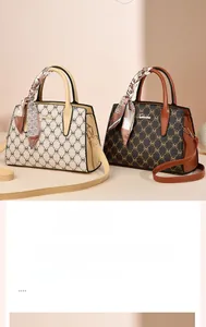 Detail of elegant handbags with monogram patterns and silk scarf decor on handles