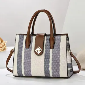 Detail of woven bicolor handbag with brown leather trim and golden diamond rotary lock