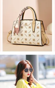 Detail of cream tote bag with monogram print, silk scarf on handle, and gold logo plaque