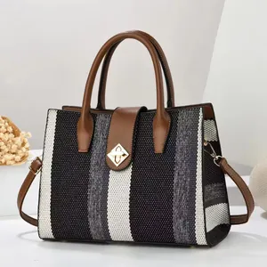 Detail of tricolor woven texture handbag with brown leather trim and golden metal clasp