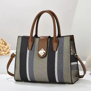 Large capacity striped tote bag with brown leather trim and golden twist lock