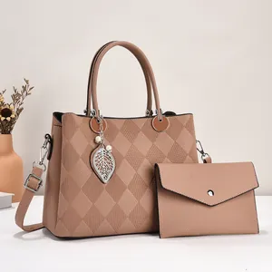Detail view of pink tote and envelope bag set with faux leather lychee texture and leaf charm