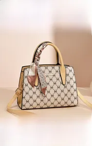Detail of beige handbag with M monogram print, golden logo plate, and decorative silk scarf