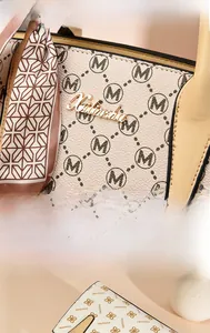 Close-up of beige monogram handbag featuring gold metal logo and floral silk scarf detail