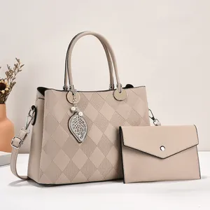 Quilted beige tote bag set with matching clutch and pearl leaf charm in indoor setting