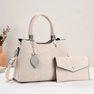 Detail view of cream crossbody handbag with matching wallet and metal leaf charm