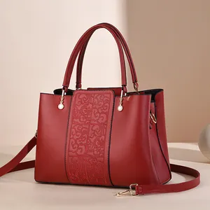 Elegant red leather handbag with traditional embroidery and detachable gold-tone strap