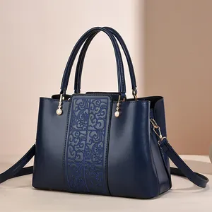 Dark blue leather handbag with elegant embroidery, top handles, and pearl charm detail