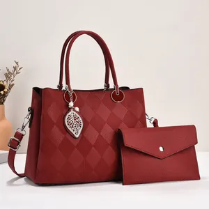 Detail of wine red tote bag with quilted pattern, silver leaf pendant and inner pouch