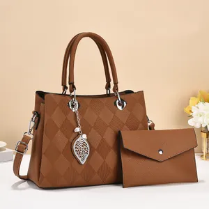 Detail of caramel brown quilted tote bag with leaf pendant and matching envelope clutch