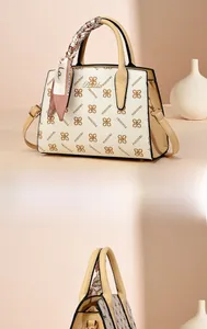 Detail of a beige tote bag with clover monogram pattern and decorative silk scarf on handle